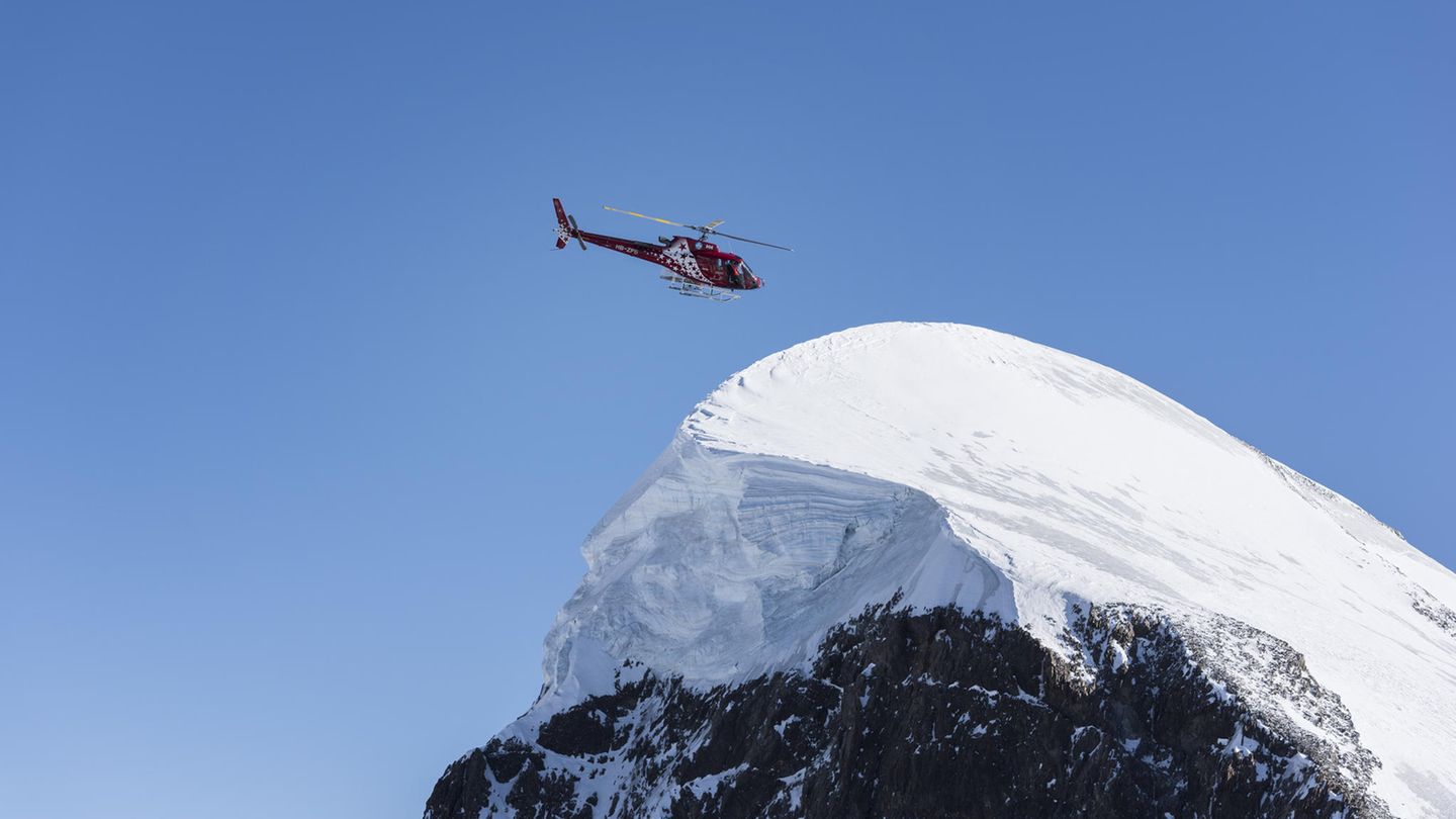 Rettungshelikopter von Air Zermatt fliegt über ein Schneefeld in den Walliser Alpen