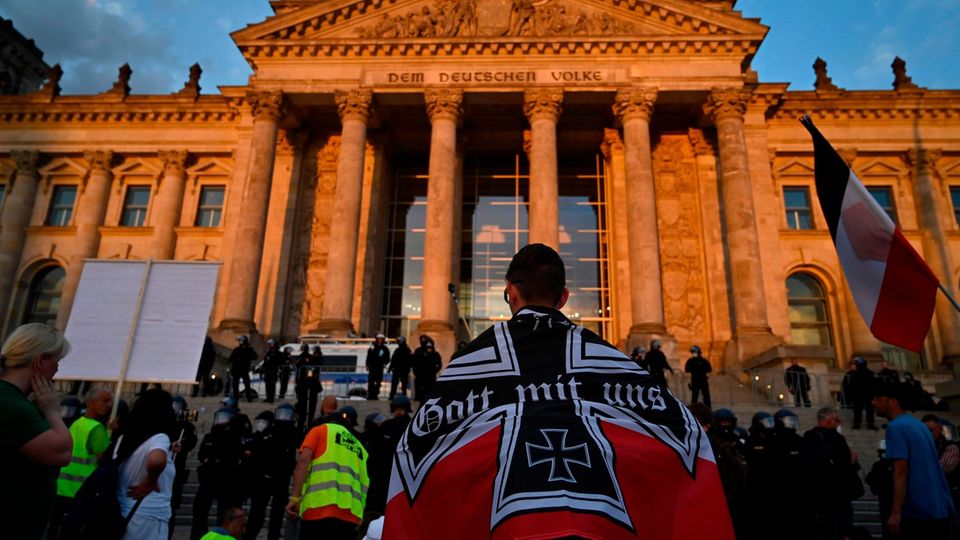 Berlin: Ein Demonstrant, eingewickelt in eine schwarz-weiß-rote kaiserliche Reichsflagge, vor dem Reichstagsgebäude