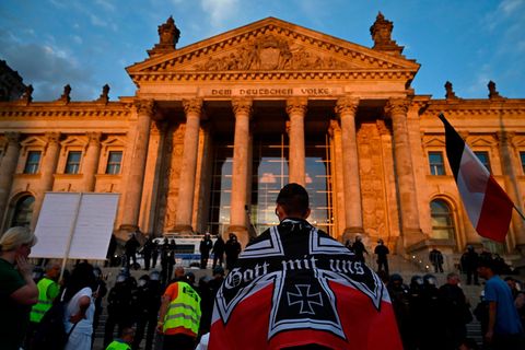 Berlin: Ein Demonstrant, eingewickelt in eine schwarz-weiß-rote kaiserliche Reichsflagge, vor dem Reichstagsgebäude