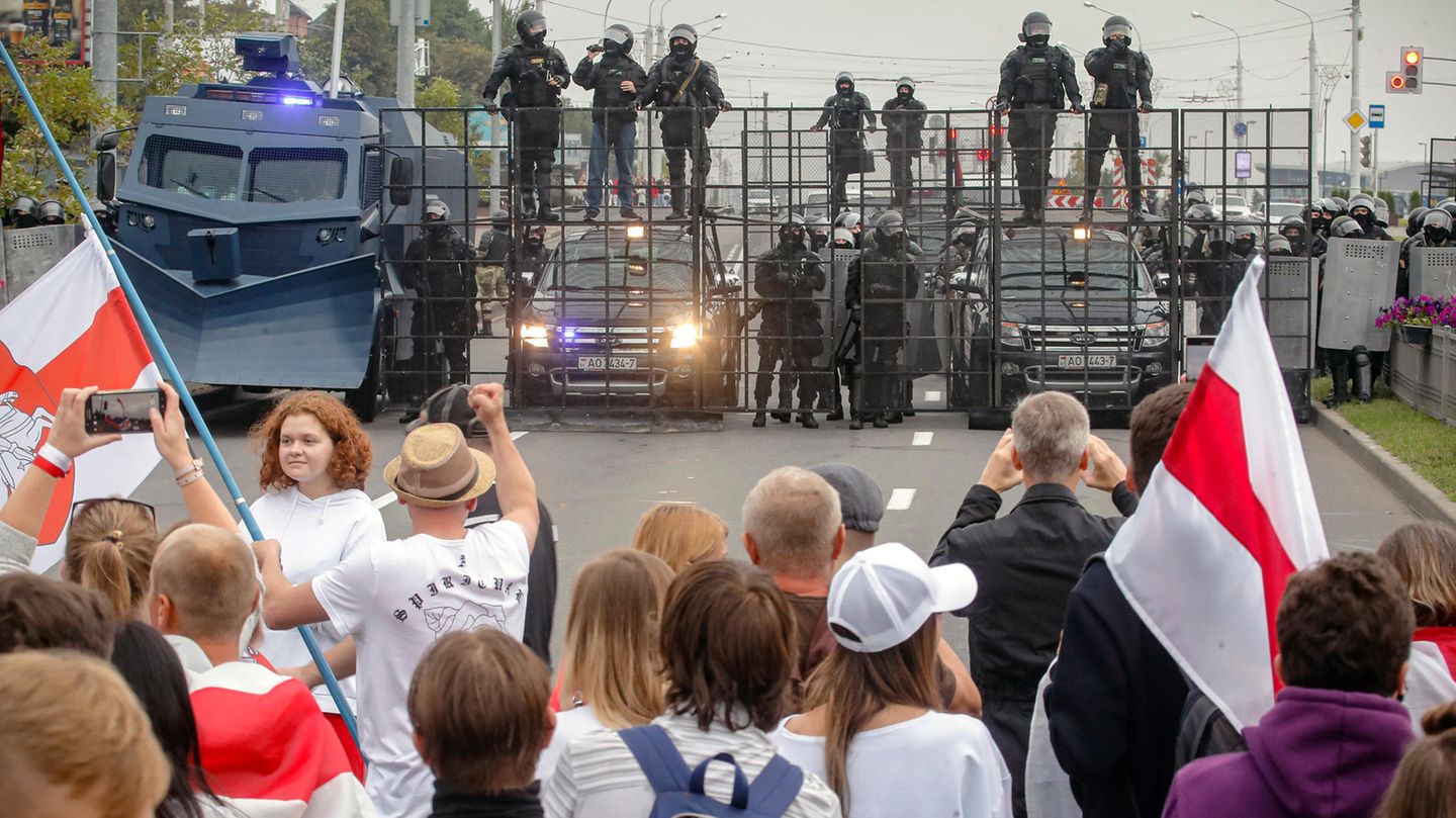 Demonstranten und Bereitschaftspolizisten stehen sich auf einer Straße in Minsk gegenüber Demonstranten und Bereitschaftspolizisten stehen sich auf einer Straße in Minsk gegenüber