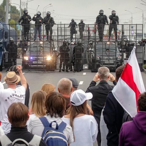 Demonstranten und Bereitschaftspolizisten stehen sich auf einer Straße in Minsk gegenüber