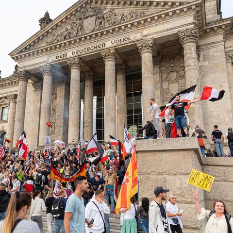 Demonstranten mit Reichsflaggen stehen auf den Stufen vor dem Reichstag in Berlin