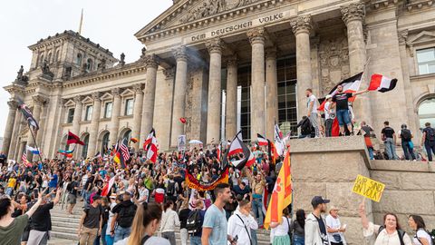 Demonstranten mit Reichsflaggen stehen auf den Stufen vor dem Reichstag in Berlin