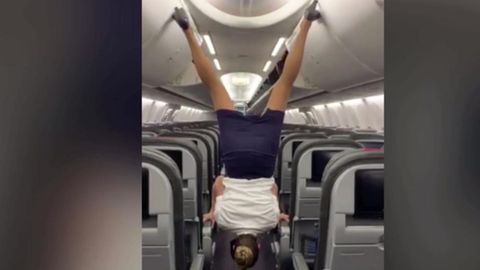 Stewardess schließt Gepäckablage kopfüber mit High-Heels