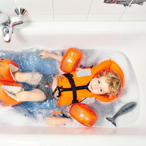 Ein Kind mit Schwimmflügeln in der Badewanne
