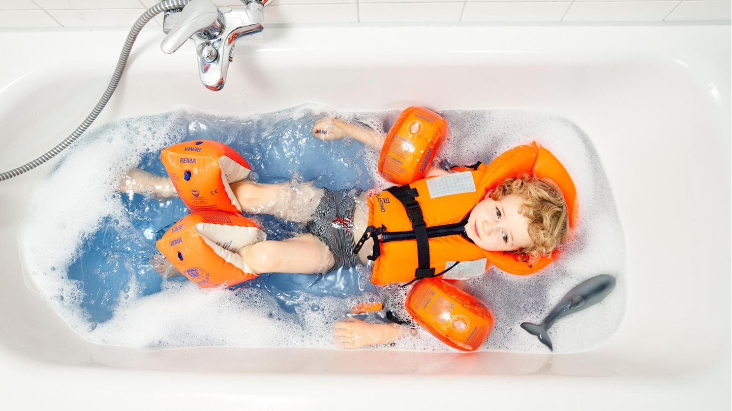 Ein Kind mit Schwimmflügeln in der Badewanne Ein Kind mit Schwimmflügeln in der Badewanne