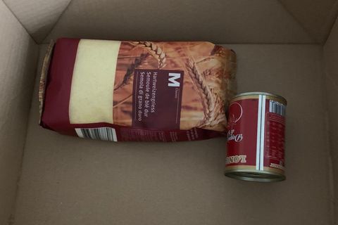 Ein Pfund Hartweizengrieß und eine Dose Tomatenmark liegen in einem Karton