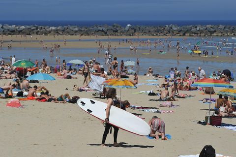 Der gefüllte Strand mit einer Surferin
