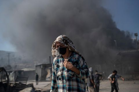 Eine Frau mit Mund- und Kopfbedeckung im zerstörten Flüchtlingslager Moria auf Lesbos