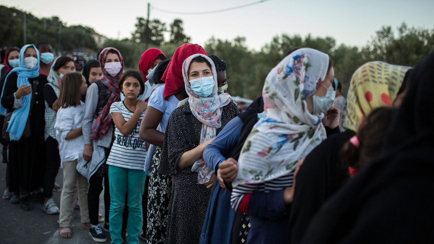 Frauen stehen an, um Essen zu erhalten, in der Nähe des ausgebrannten Flüchtlingslagers Moria