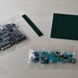 Im Karton befinden sich in zwei Tütchen mit den Bauteilen sowie die grüne Grundplatte, die zusammengesetzt eine Größe 14,5 mal 13 Zentimeter ergibt.