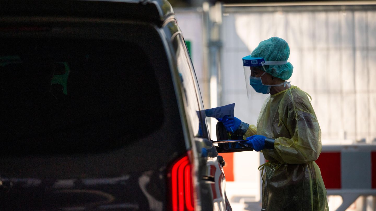 Garmisch-Partenkirchen: Eine Mitarbeiterin gibt in einem Testzentrum einer Familie in einem Auto Infomaterial zum Coronavirus