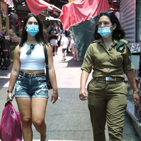 Israelis, die Nasen- und Mundschutz tragen, gehen durch einen Markt