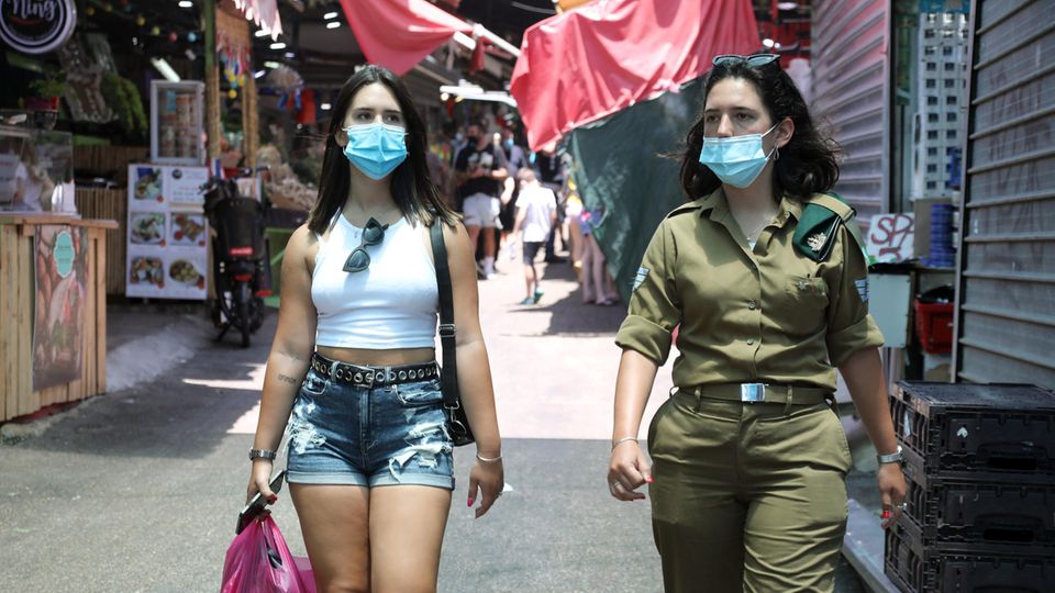 Israelis, die Nasen- und Mundschutz tragen, gehen durch einen Markt