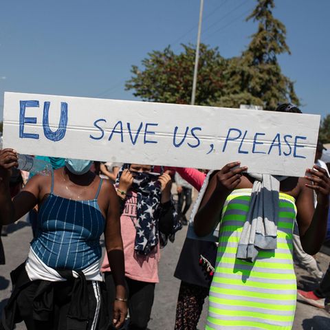 Migranten protestieren auf Lesbos mit einem Schild "EU save us, please!"