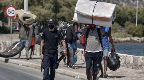 Polizist begleitet Flüchtlinge aus Moria in ein neues Camp