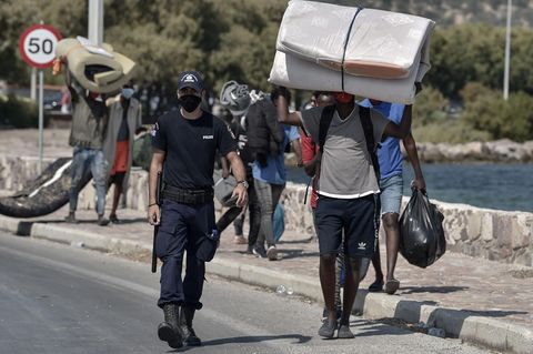 Polizist begleitet Flüchtlinge aus Moria in ein neues Camp