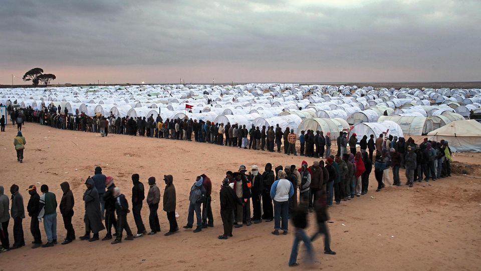 RAS JDIR, TUNISIA - MARCH 08: Men who recently crossed into Tunisia from Libya wait in line for food in a United Nations displacement camp on March 08, 2011 in Ras Jdir, Tunisia. As fighting continues in and around the Libyan capital of Tripoli, tens of... Geflohene Gastarbeiter in Tunesien