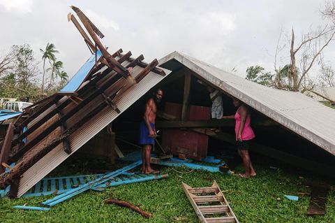 Familie steht auf Vanuatu in den Trümmern ihres durch einen Wirbelsturm zerstörten Hauses
