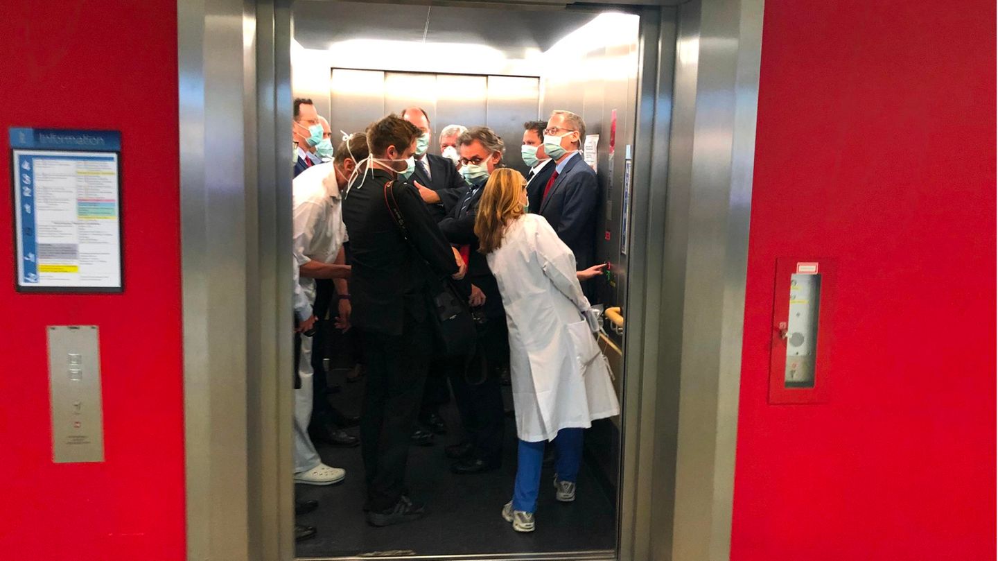 Volker Bouffier, Jens Spahn und andere Personen stehen dicht gedrängt im Aufzug