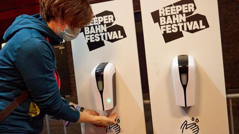 Eine Konzertbesucherin desinfiziert sich an einem Spender ihre Hände vor dem Eingang zum Grünspan in Hamburg