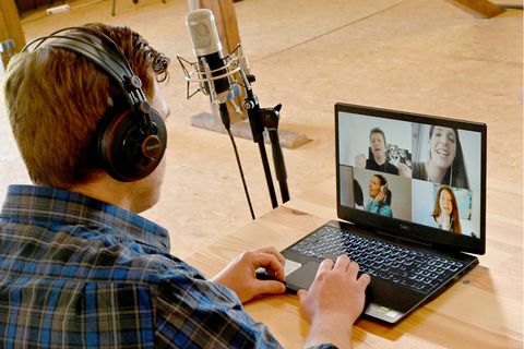 Ein Mann in blauem Karohemd sitzt an einem Laptop, auf dessen Monitor die Gesichter von vier Jugendlichen zu sehen sind