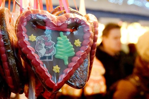 Ein Lebkuchenherz mit einem Tannenbaum und einem Weihnachstmann hängt an einem Stand auf einem Weihnachtsmarkt