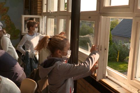 Schüler schließen die Fenster in ihrem Klassenraum.