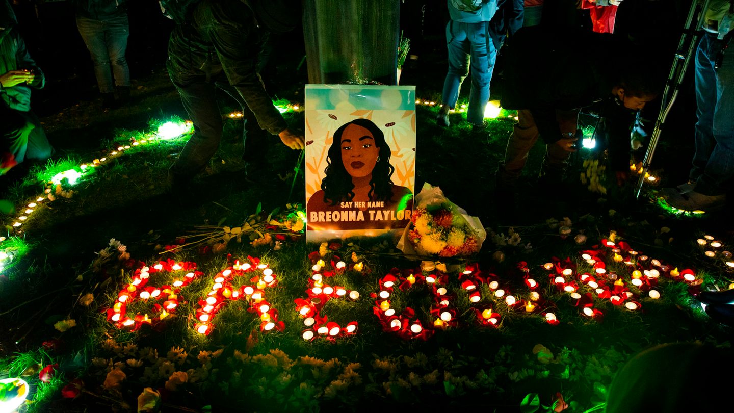 Auf einem Stück Rasen steht ein gemaltes Porträt einer Afroamerikanerin. Darunter mit Kerzen der Name "Breonna"