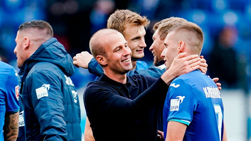 TSG 1899 Hoffenheim - FC Bayern München Bundesliga Ein Mann mit kurzrasierten Haaren umarmt einen Fußballer im blauen Trikot mit weißen Aufdrucken