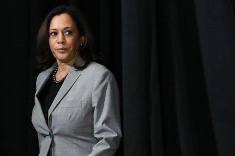 Kamala Harris tritt vor einem dunklen Vorhang auf eine Bühne