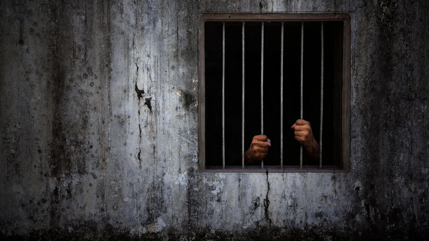 Die Hände eines Mannes hinter Gittern Die Hände eines Mannes hinter Gittern