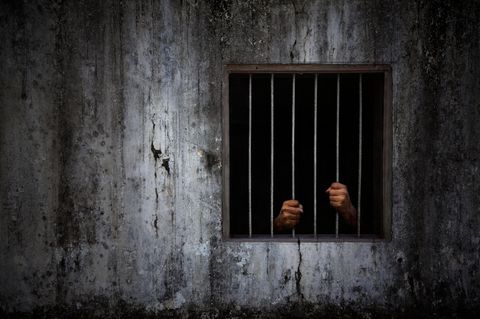 Die Hände eines Mannes hinter Gittern