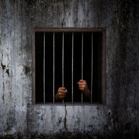 Die Hände eines Mannes hinter Gittern