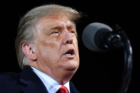 US-Präsident Donald Trump steht hell angeleuchtet in einer Halle und spricht in ein Mikrofon