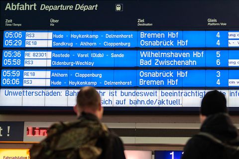 Verspätungen: Reisende stehen am Morgen am Bahnhof und schauen zur Anzeigetafel der Deutschen Bahn: