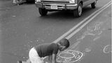 Boy writing OWL with chalk on street, Lower East Side, Manhattan, NYC, 1978