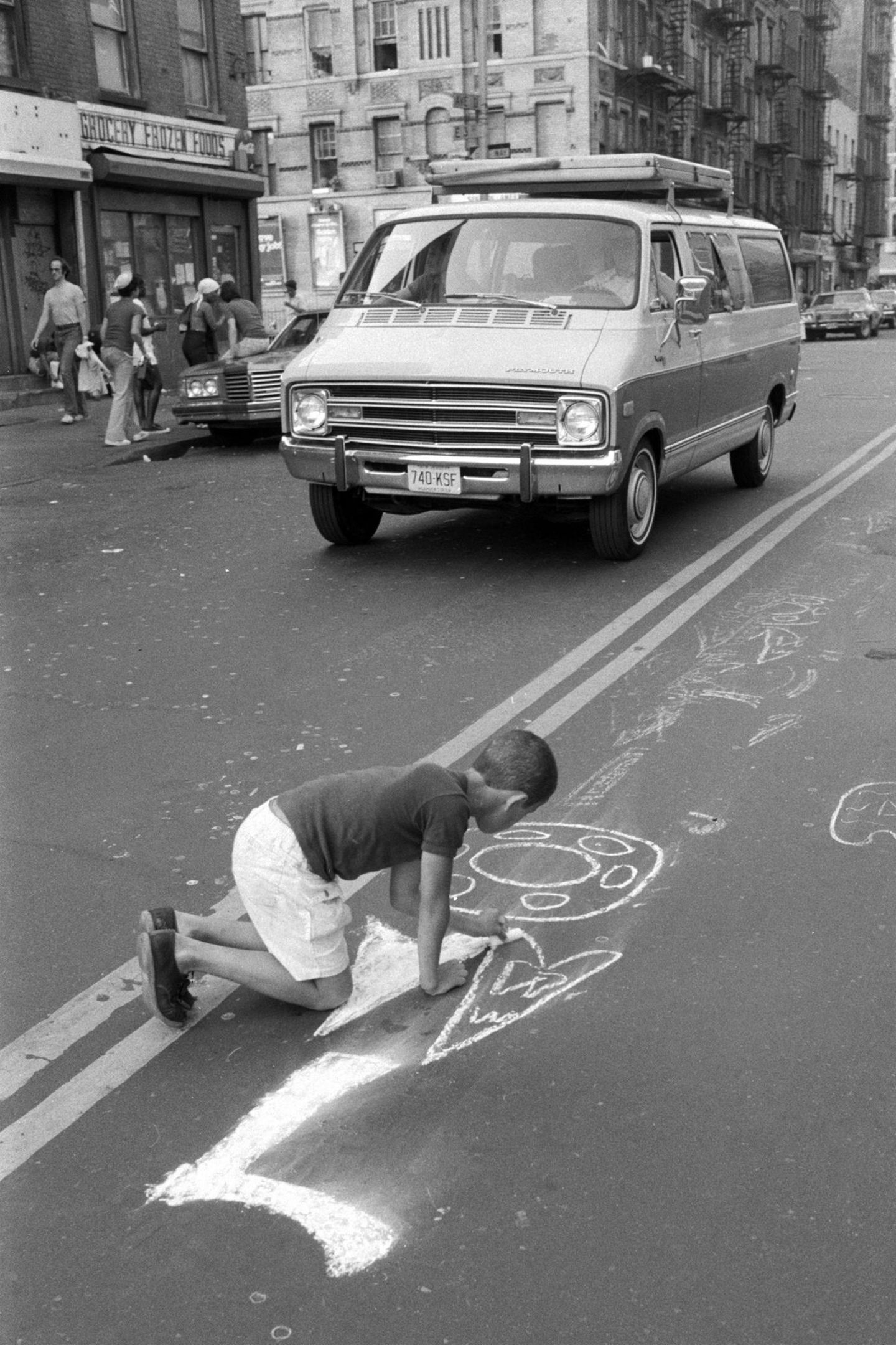 Boy writing OWL with chalk on street, Lower East Side, Manhattan, NYC, 1978