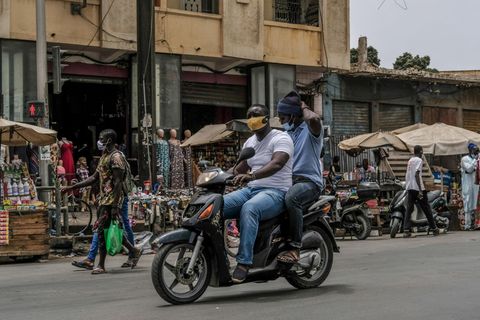 Coronavirus Afrika: Zwei Männer mit Schutzmasken fahren zusammen auf einem Motorroller