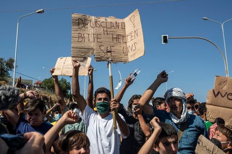 Griechenland, Lesbos: Flüchtling hält ein Plakat mit der Aufschrift "Deutschland, bitte helfen Sie uns".
