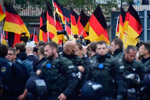 Polizisten bei einer Demonstration; im Hintergrund sind zahlreiche Deutschlandfahnen zu sehen.