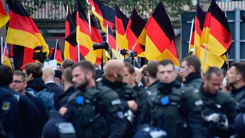 Polizisten bei einer Demonstration; im Hintergrund sind zahlreiche Deutschlandfahnen zu sehen.