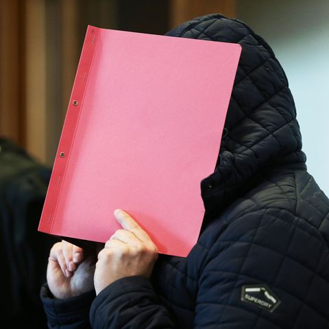 Landgericht Köln: Der Angeklagte verdeckt sein Gesicht mit einem roten Umschlag