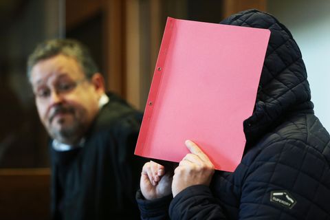 Landgericht Köln: Der Angeklagte verdeckt sein Gesicht mit einem roten Umschlag