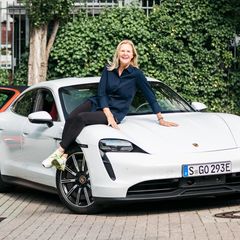 Daniela Sachs Rollmann sitzt auf der Motorhaube des Porsche Taycan