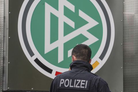 Razzia beim DFB: Ein Polizeibeamter steht am Logo des DFB vor der Zentrale in Frankfurt/Main