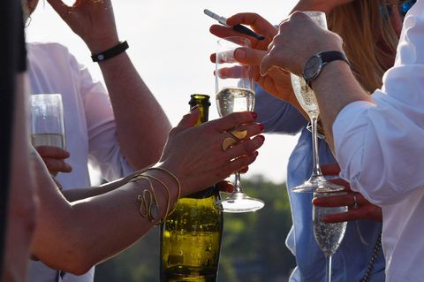 Partygäste halten Gläser mit Prosecco in den Händen.