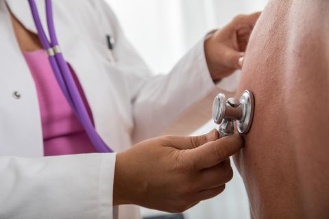 Eine Ärztin hört die Lunge eines Patienten ab