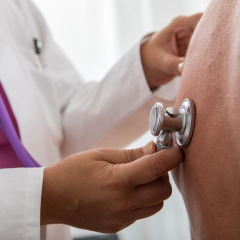 Eine Ärztin hört die Lunge eines Patienten ab