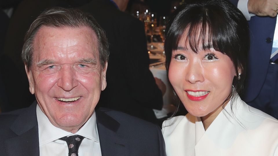 Gerhard Schröder und Soyeon Kim Altkanzler Gerhard Schröder im Anzug und seine Frau Soyeon Kim im weißen Blazer lächeln in die Kamera